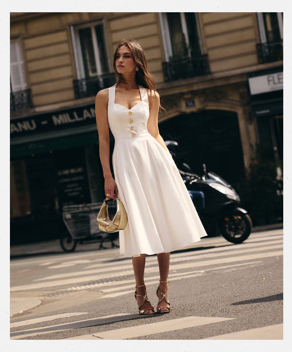 Woman in a white dress standing on a city street