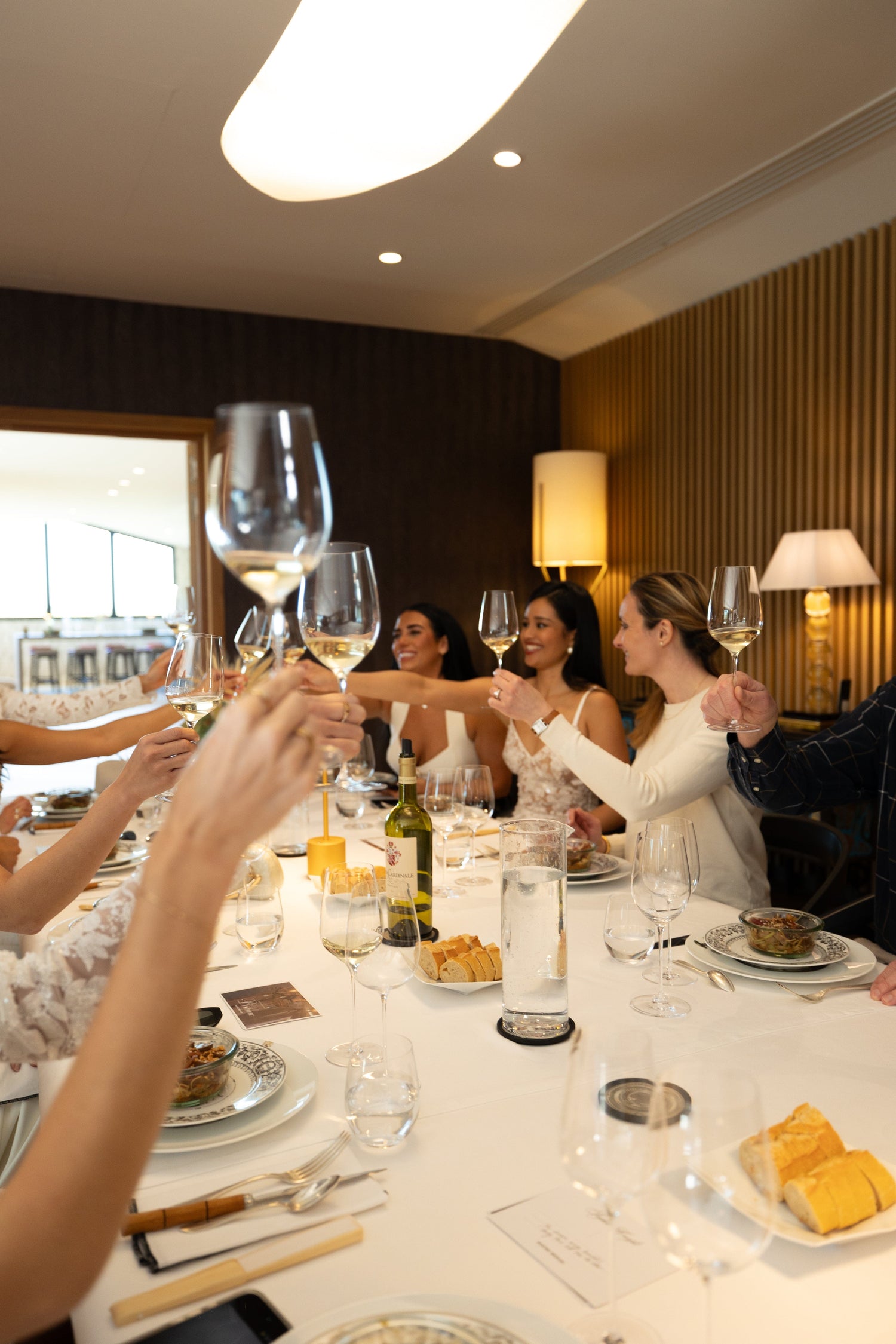 Group of people at a dinner table with wine glasses, enjoying a meal.