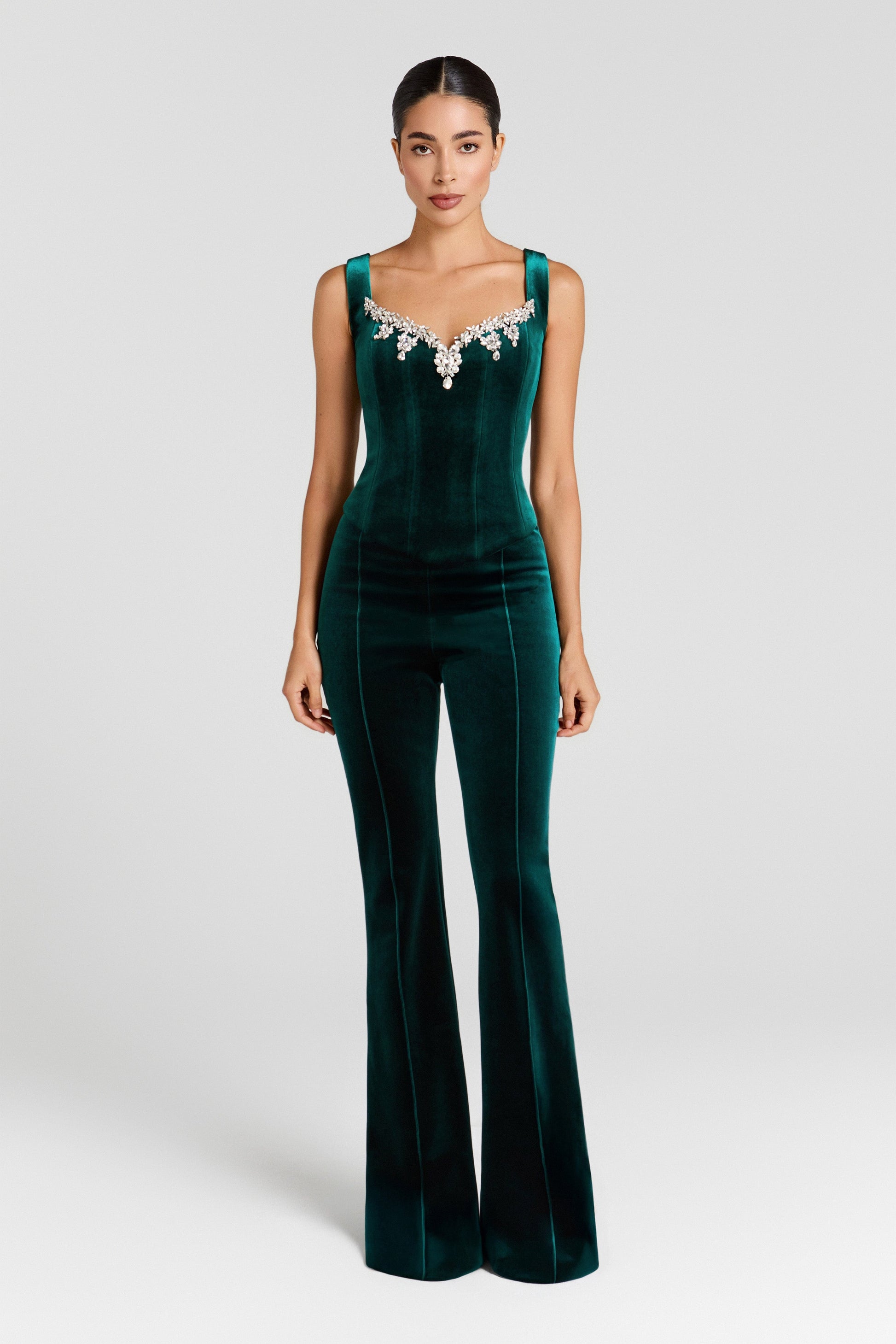 Green velvet jumpsuit with embellishments on a white background