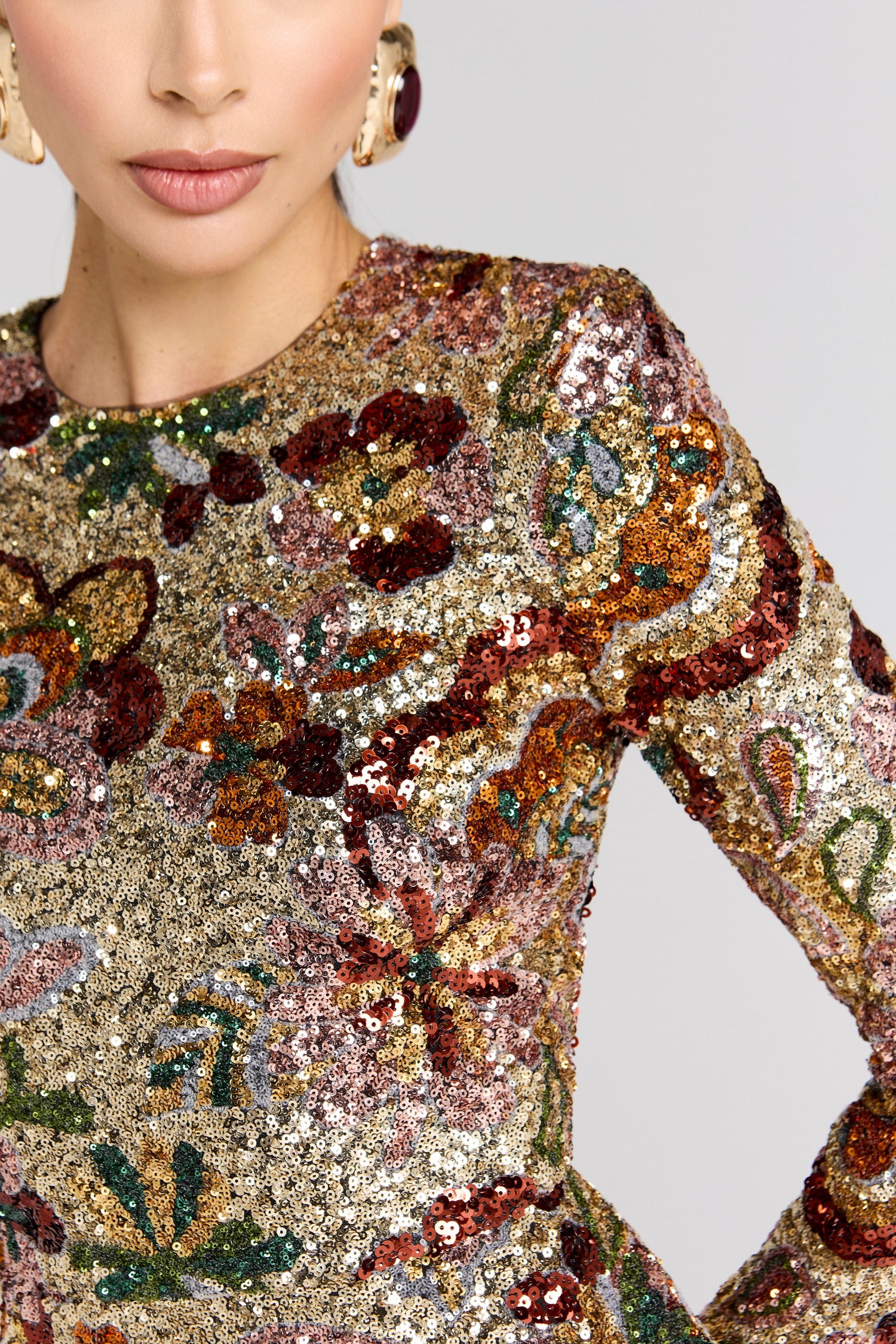 Close-up of a person wearing a sparkling, multicolored sequin dress with floral patterns.