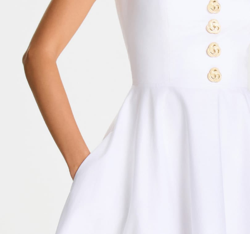 White dress with gold buttons on a plain background