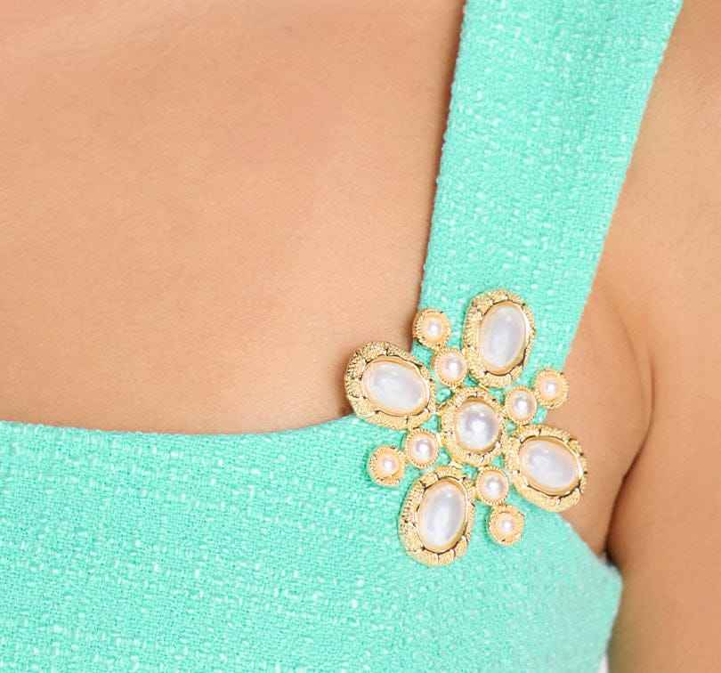 Gold brooch with pearls on a turquoise garment