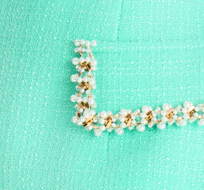 Pearl and gold bracelet on a turquoise background