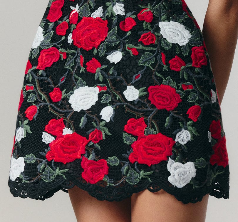 Black lace skirt with red and white floral embroidery on a neutral background