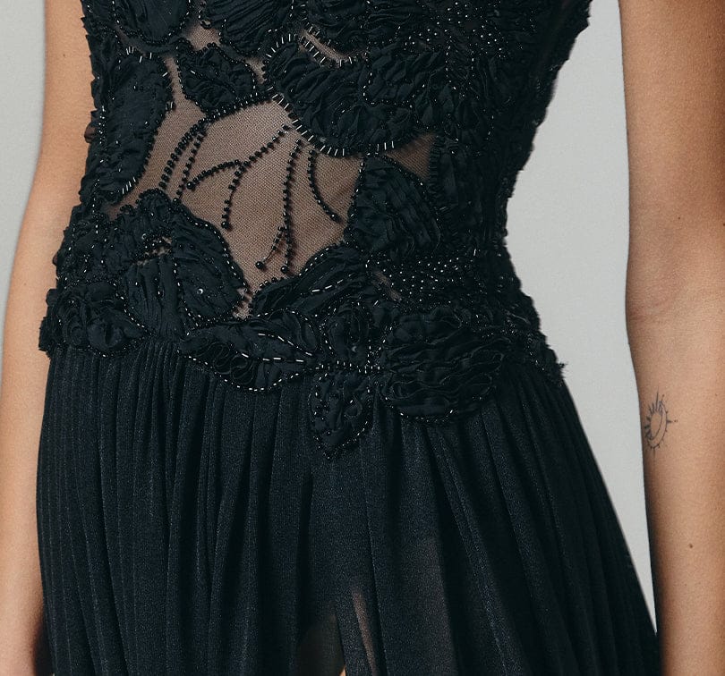 Black dress with floral embellishments on a neutral background