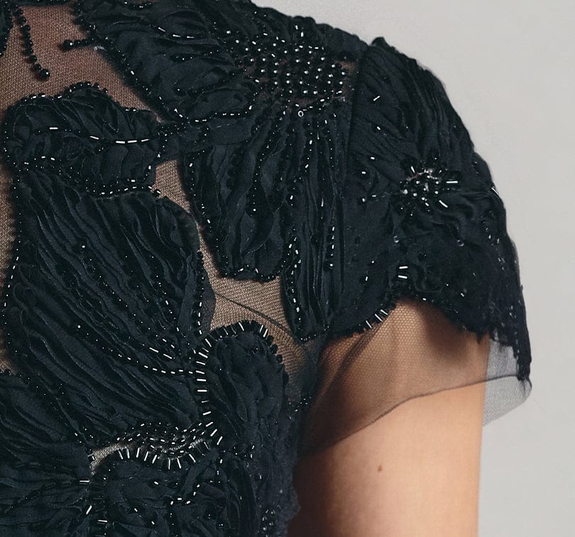 Close-up of a black embroidered garment with a neutral background