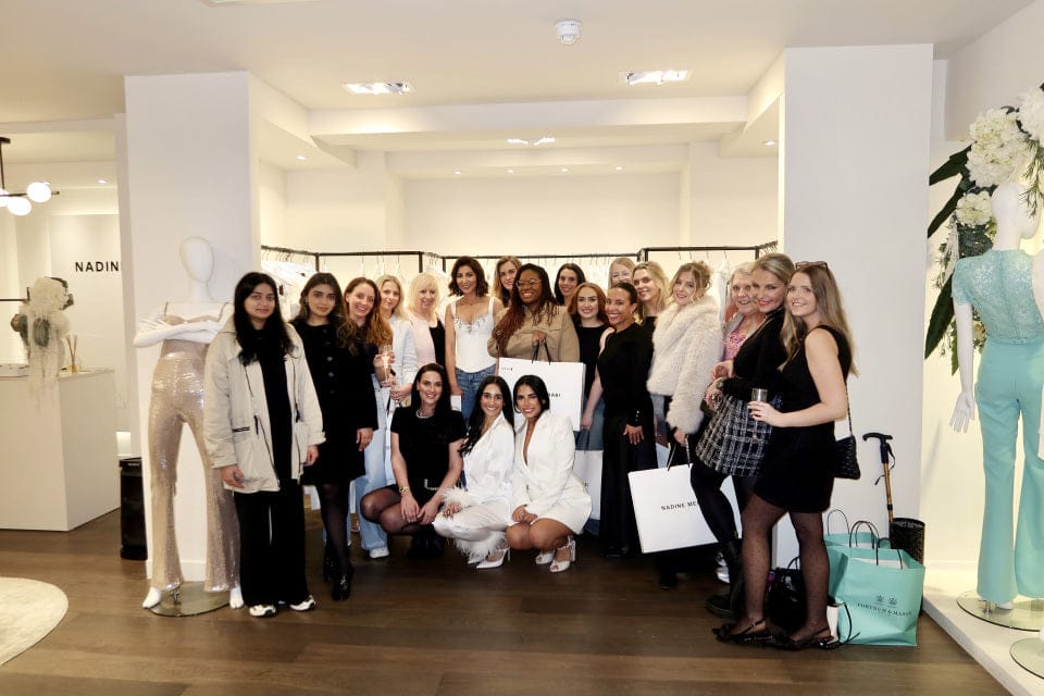 Group of women posing together in a store with fashion displays in the background