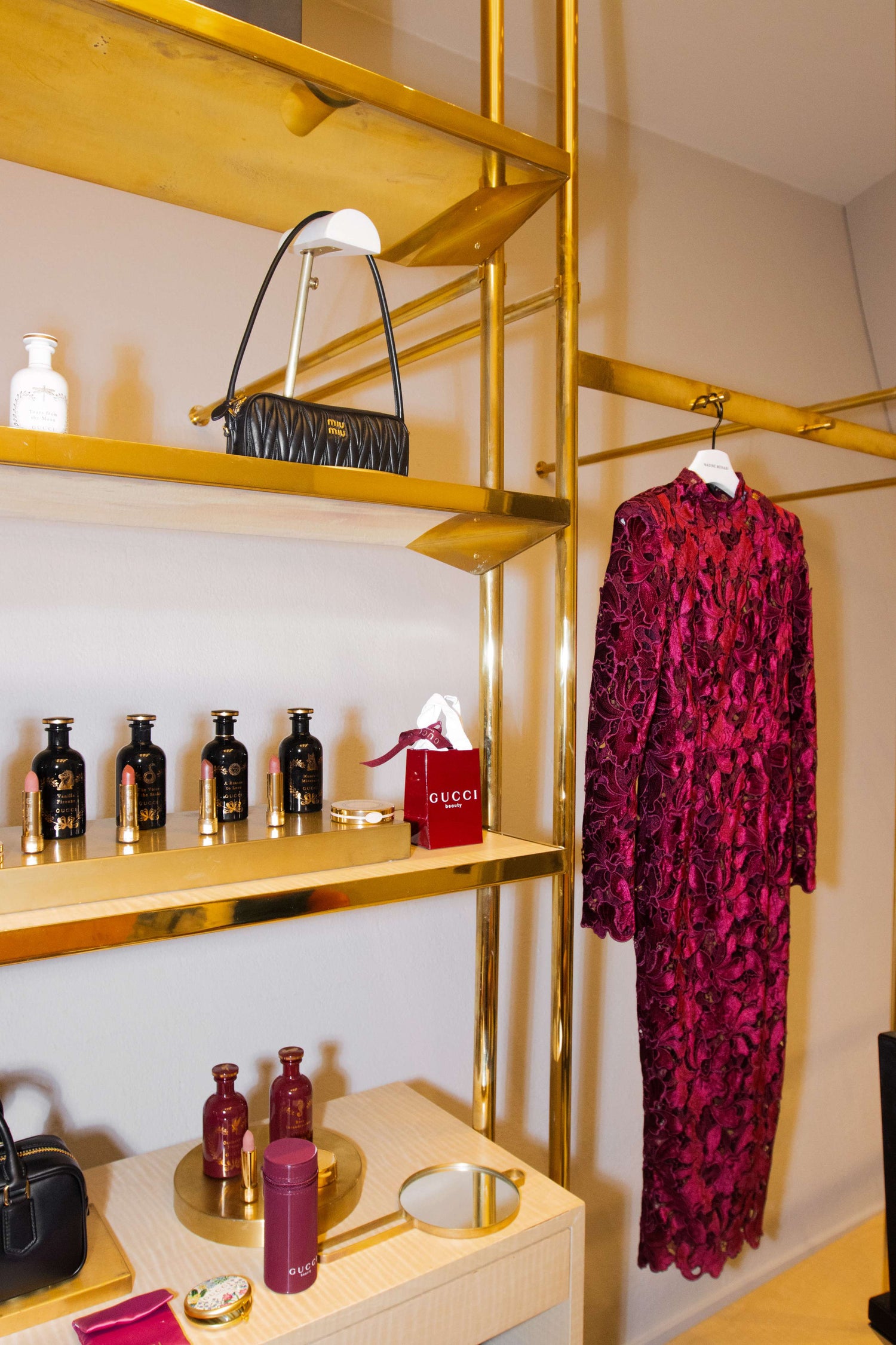 Gold shelves with a red patterned dress, black handbag, and Gucci products.