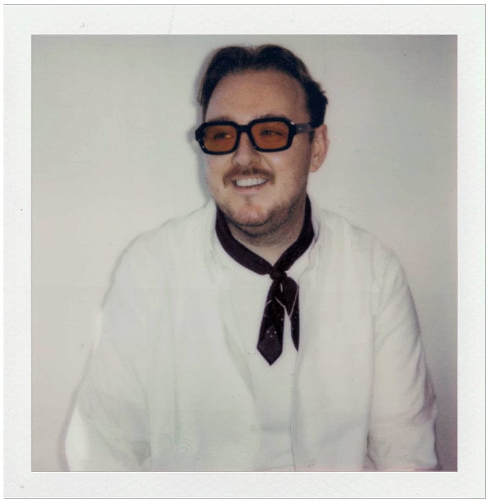 Person wearing a white shirt and dark tie with a plain background