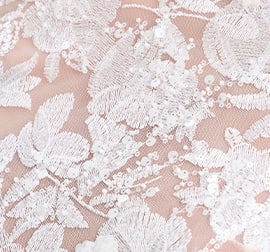 Close-up of white lace fabric with floral patterns on a pink background