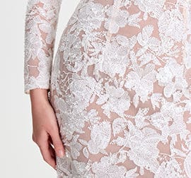 Close-up of a white lace dress with floral patterns on a light background