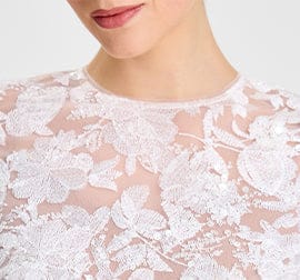 Close-up of a person wearing a white lace garment on a light background